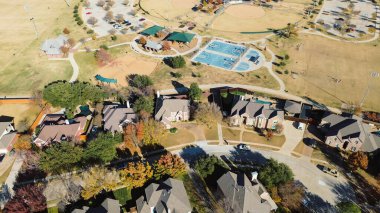 Park tarafındaki lüks banliyö mahallelerine, basketbol sahalarına, çoklu oyunculara, yeşil gölgelik oyun parkına yaprak dökün. Açık arazilere giden eğimli yürüyüş yolları, sınır evleri, Coppell, Teksas. ABD