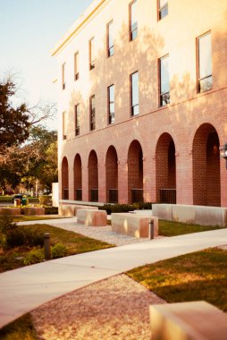 Çok katlı tuğla yapı üniversite kampüsünde kemerli zemin katlı açıklıklar ve dikdörtgen şeklinde üst pencereler var. Çakıl yatakları, beton banklar ve ağaç gölgeleri Waco, Teksas 'taki cepheyi canlandırıyor. ABD