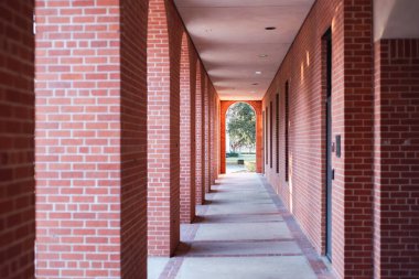 Dikdörtgen tuğlalı sütunlarla kaplı, beton döşemeler parlak kemer yoluna doğru uzanıyor. Gölgeler simetrisi, uzak çitlere, ağaçlarla kaplı çimenlere üniversite kampüsüne, Waco 'ya, TX' e rehberlik eder. ABD