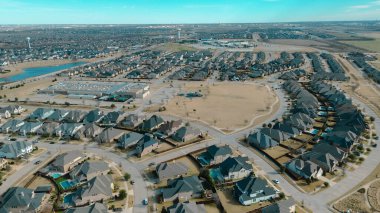 Eğri caddelerin yanındaki okul kampüsü ve oyun alanı havuzlu ve manikürlü bahçeli banliyö evleri, Central Park, Prosper, Teksas entegrasyonu, dinlenme, yerleşim planlama. ABD