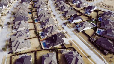 Comact Prosper, Texas mahallesindeki geniş banliyö evleri. Üniformalı çatılar, çitli bahçeler, havuzlar, manikürlü çimenler dairesel amfitiyatrosu olan yapılandırılmış banliyö yerleşimi vurgulanıyor. ABD