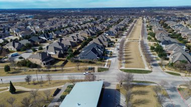 Prosper, Teksas 'ta kış sokak manzarası. Uzun ağaç sıralı medyan, üniformalı evler ve mevsimlik dekor, organize banliyö planlama ve mahalle simetrisiyle şenlikli bir topluluk alanı var. ABD