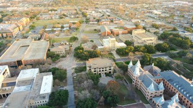 Waco, TX 'teki üniversite kampüsünde trafik akışı olan, kırmızı tuğlalı akademik binalar, ağaçlı kaldırımlar, I-35 N Frontage Yolu yakınlarındaki yapılandırılmış park alanları ile çevrili bir çevre. ABD