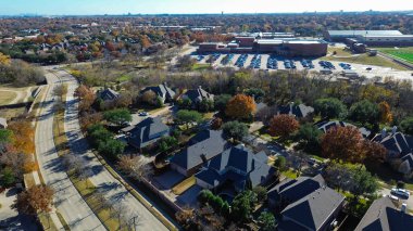 Resim, bölünmüş otoyol yolu ile aynı hizaya gelir, toplumu nasıl ikiye ayırdığını vurgular. Lüks evlerden geniş akademik ve atletik alanlar olan Coppell, Texas 'a geçişi kaydeder. ABD