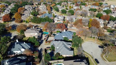 Gri ve kahverengi çatıları olan Coppell evleri, Dallas, Teksas 'ın sakin bir banliyösünde havuz, çit ve canlı sonbahar ağaçları temiz sokakları ve manikürlü çimenleri çerçeveler. ABD