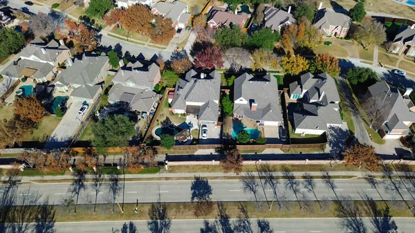 Coppell evlerinin arka bahçeleri, havuzları ve kesişen caddeleri olan satırları; sonbahar ağaçları uzun gölgeler bırakarak mülkiyet ölçeğini, yerleşim planını ve komşuluk bağlantısını ön plana çıkarıyor, Teksas. ABD