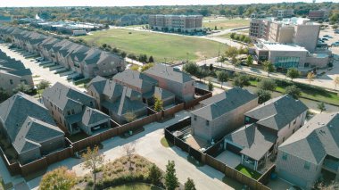 Garden Ridge Bulvarı yakınlarındaki bir kanala çitli bahçeli iki katlı evler. Tuğla tonları ve pergola gölgeleri manzaralı ön plan ve yürüyüş yolu olan Flower Mound, Texas 'ı çerçeveler. ABD