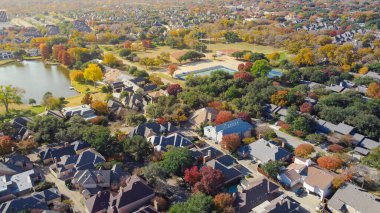 Churchill Yolu ve Hillcrest Bulvarı yakınlarındaki lüks halk parkında tenis kortları, beyzbol sahaları ve göl görünüyor. Renkli yapraklar, çeşitli çatılar, yumuşak ışıklandırma mevsimsel dokuyu tanımlar, Kuzey Dallas, Teksas. ABD