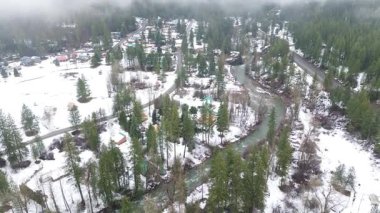 Peshastin Deresi koridorundaki evler kavisli yerel yolların yakınında ve karavan parkının güneyinde orman yamaçları. Karlı çatılar, buzlu su dokuları, sisli ağaç tepeleri Peshastin, Washington