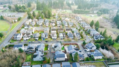 Meridian Platosu yakınlarındaki yerleşim yerleri Maple Valley yaklaşımına ve Panther Gölü koridoruna doğru uzanıyor. Karışık çatı tonları, dağınık araçlar, serin gün ışığında katmanlı ağaç tepe örtüleri, Kent, WA. ABD