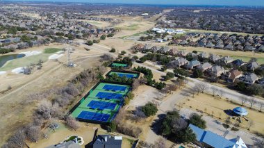 Lantana golf koridoru yakınlarındaki tenis kompleksi pavyonun, su tehlikesinin ve yerleşim yerlerinin yanında yer alır. Mavi yeşil kortlar, metal çatılar, kış çimenleri, yumuşak gündüz eğlence dokuları, Lantana, TX. ABD