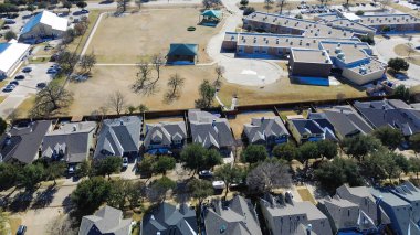 Tanner Parkway okul kompleksi yakınındaki açık alanlar ve pavyon binaları. Çıplak ağaçlar, sessiz çim, havalandırma, kış ışıkları Lantana ve TX 'te katmanlı görsel dokular oluşturur. ABD