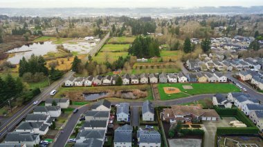 Hava manzaralı, yarı kırsal Doğu Tepesi parselleri. 1960. Cadde yakınlarındaki çalılık ve ormanla çevrili sulak alan göletine doğru geçiş. Yıpranmış çatılar, yamalı çimenler, yumuşak gri ışıklandırma Kent 'i tanımlıyor, WA. ABD