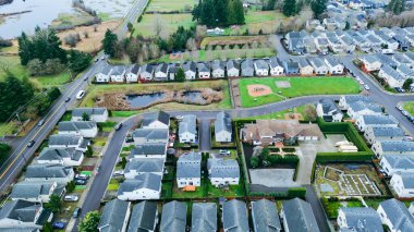 Yoğun Doğu Tepesi ızgarası ağaçlık yamaçlara, tekdüze evlere, sahil kenarına ve oyun parkına doğru uzanıyor. Tarafsız kiremitler, dağınık ağaçlar, havuz, göl ve Washington 'daki sulak arazi. ABD
