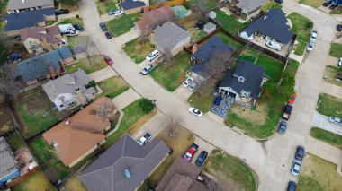 Cravens Park koridorunun güneyindeki virajlı sokaklar dar aralıklı evleri, garaj yolunu gösteriyor. Çatı renk değişimi, yapraksız ağaçlar, soluk çimenler, yumuşak kış ışığı, yerleşim tonu, Arlington, TX. ABD