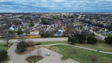 Cravens Park 'ın kuzey ucundaki evler kavisli yolun ve açık yeşil alanın yanında yer alır. Karışık kiremitler, çıplak ağaçlar, soluk çimenler, yumuşak bulutlu ışık, Arlington, Teksas 'ta sessiz kış dokusu. ABD