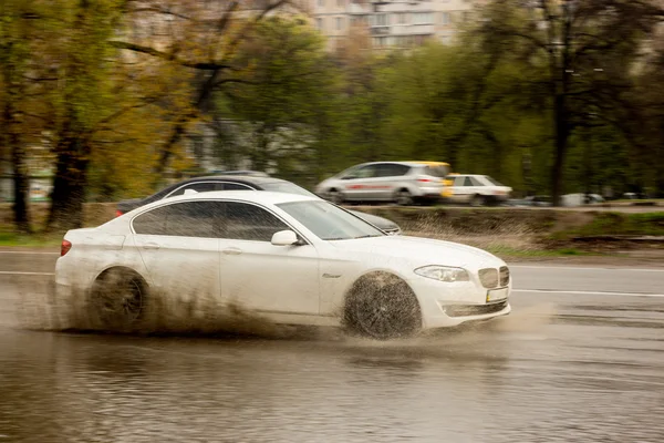 Splashes from under the wheels of a passing car through — Stock Photo, Image
