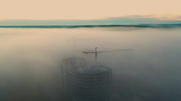 Unfinished high-rise buildings in the fog at dawn. — Stock Video