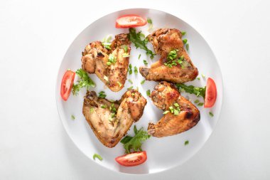 Beyaz arka planda fırında tavuk kanadı. Protein ve karamelize yağ açısından yüksek bir ürün..