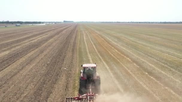 Landbouwwerkzaamheden met een trekker. De trekker bestuurder speelt de grond met een schijveneg. — Stockvideo