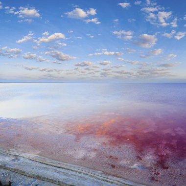 Lemuria Gölü 'nde gün batımı. Kırmızı tuz kıyıda uzanıyor. Bulutlar su yüzeyine yansıyor..