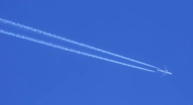 Mavi gökyüzünün arka planında uçaktan gelen beyaz yansıma izi.