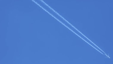 Mavi gökyüzünün arka planında uçaktan gelen beyaz yansıma izi.