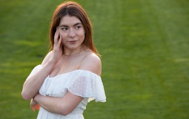 Parktaki sokakta gülümseyen beyaz elbiseli çekici esmer. Portre