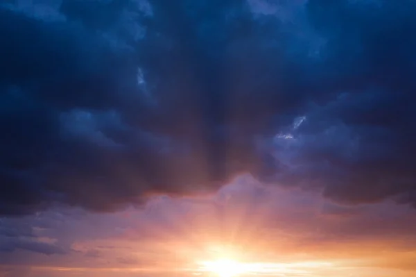 Cáncer azul cielo tormentoso con rayos de sol. — Foto de Stock
