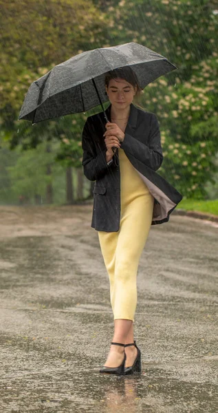 Ragazza sotto un ombrello nero durante la pioggia. — Foto Stock