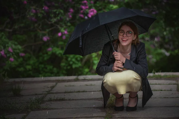 Ragazza sotto un ombrello nero durante la pioggia. — Foto Stock