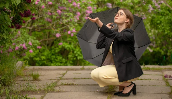 Ragazza sotto un ombrello nero durante la pioggia. — Foto Stock