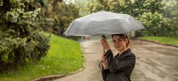 Bruna attraente sotto un ombrello cattura gocce di pioggia. — Foto Stock