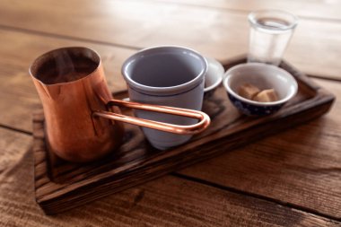 Classic Turkish coffee. Wooden tray, coffee cup, chocolate, cookies and copper turk on a wooden table.