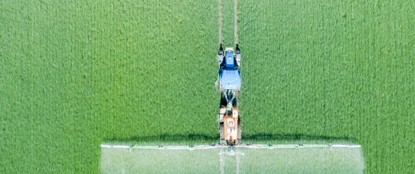 トラクターは 緑のフィールドに除草剤 農薬や肥料を適用します — ストック写真