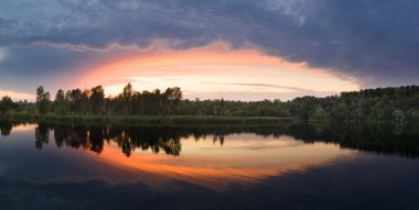 Kıpkırmızı gün batımı gölün suyuna yansıyor. Güzel bir yaz sabahı manzarası..