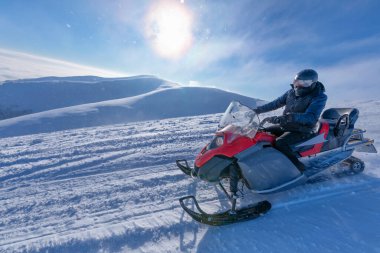 Şafakta, karlı bir dağ yolunda kar motosikleti sürüyor..