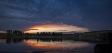 Kıpkırmızı gün batımı gölün suyuna yansıyor. Güzel bir yaz sabahı manzarası..