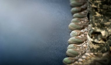 Askerlerin bacakları ayak bileği botları ve kamuflaj pantolonu giymişti. Yakın çekim, seçici odaklanma.