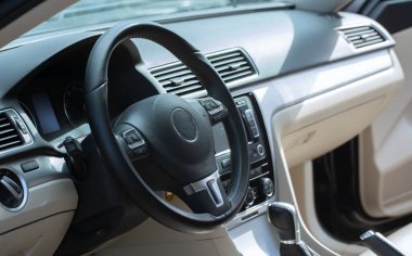 Modern araba iç mimarisi. Sürücü koltuğu beyaz, siyah deri ve metalle süslenmiş. Araba panelinde modern elektronik cihazlar.