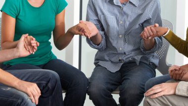 Birbirinin elini tutan ve birlikte dua eden insanların yakın çekimi.