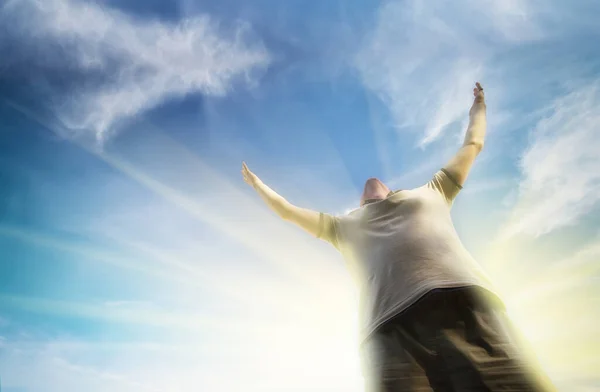 İnsanlar Tanrı 'ya açık mavi gökyüzüyle taparlar. Kollarını kaldırmış bir adamın silueti.