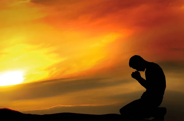 夕日を背景に瞑想男のシルエット 男はひざまずいて祈る — ストック写真