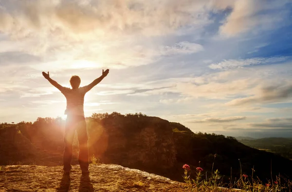 Dağın tepesinde ellerini kaldırmış bir adam.