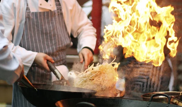 Şefin elleri tavayı ateşle yakar. Yakın aşçı elleri yemeklerini ateşle pişirir.