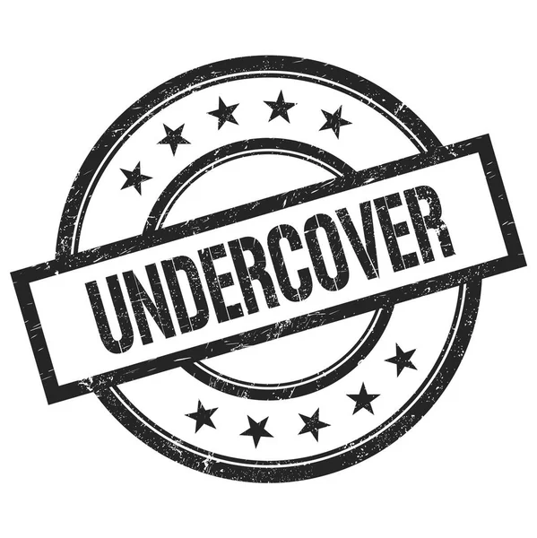 UNDERCVER metin siyah yuvarlak vintage kauçuk damga üzerine yazılmış.