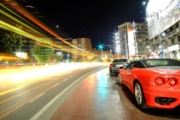 Conceito de velocidade - Carro esportivo vermelho em luzes de tráfego noturno — Fotografia de Stock