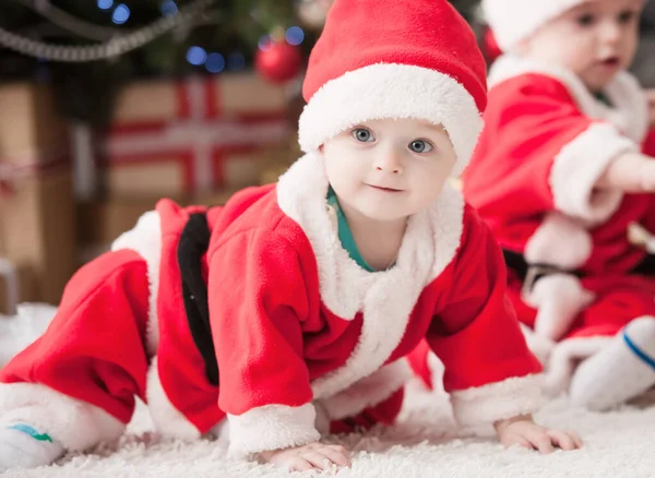 Noel ağacında hediyelerle Noel Baba gibi giyinmiş çocuklar.
