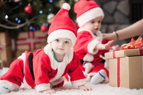 Noel ağacında hediyelerle Noel Baba gibi giyinmiş çocuklar.