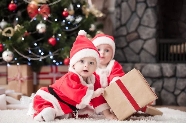 Noel ağacında hediyelerle Noel Baba gibi giyinmiş çocuklar.